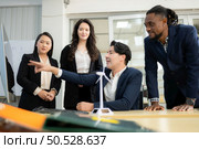 Diverse team of businessmen and engineers consultation on the engineering of a wind turbine that converts wind energy to electricity in the office. Стоковое фото, агентство Ingram Publishing / Фотобанк Лори