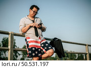 Young Asian Businessman in shirt and tie with shorts and eyeglasses standing and use smartphone in outdoor, copy space. Стоковое фото, агентство Ingram Publishing / Фотобанк Лори