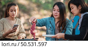 Young asian woman cooking and her friend enjoy to make the meal in pan, They are talk and laugh with fun together while camping in nature park. Стоковое фото, агентство Ingram Publishing / Фотобанк Лори