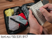 Close-up of man checks the checklist. He’s choosing clothes, travel documents, the itinerary for a solo trip. Travel, holiday and vacation concept. Стоковое фото, агентство Ingram Publishing / Фотобанк Лори