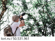 Asian traveler man with backpack taking a photo in the park with copy space. Travel photographer. Vocation and holiday concept. Стоковое фото, агентство Ingram Publishing / Фотобанк Лори