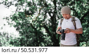 Asian Traveler man with backpack checking a picture on camera at the park with copy space. Travel photographer. Vocation and holiday concept. Стоковое фото, агентство Ingram Publishing / Фотобанк Лори