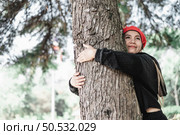 Contented young woman hugging a large tree with a blissful expression with copy space. Concept of care for environment. Стоковое фото, агентство Ingram Publishing / Фотобанк Лори