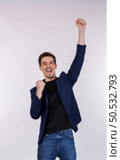 Portrait of happy joyful young businessman standing doing winner gesture clenching fists keeping isolated on white color wall background studio. Victory and success concept. Стоковое фото, агентство Ingram Publishing / Фотобанк Лори