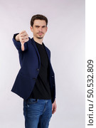 Portrait of young businessman shows sign of dislike, looks with negative expression and disapproval on isolated background. Disagreement, disgust and negative expressions. Стоковое фото, агентство Ingram Publishing / Фотобанк Лори