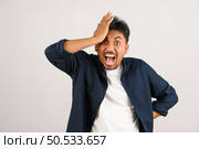 Portrait of Disappointed young asian man in blue shirt annoyed angry in furious gesture isolated on white background. Expression and lifestyle concept. Стоковое фото, агентство Ingram Publishing / Фотобанк Лори