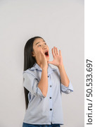 Portrait of young asian woman shout story or making announcement over isolated white background. Advertising and lifestyle concept. Стоковое фото, агентство Ingram Publishing / Фотобанк Лори