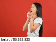 Portrait of Young asian woman in white t-shirt looking up and exciting isolated on red background. Expression and lifestyle concept. Стоковое фото, агентство Ingram Publishing / Фотобанк Лори