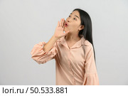 Portrait of Excited young asian woman in pink shirt shout story or making announcement over isolated white background. Advertising and lifestyle concept. Стоковое фото, агентство Ingram Publishing / Фотобанк Лори