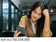 Close up, Portrait young pretty woman feel bored while looking or video call on smartphone at cafe. Стоковое фото, агентство Ingram Publishing / Фотобанк Лори