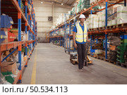 Warehouse workers pushing a pallet truck in a shipping and distribution warehouse. Стоковое фото, агентство Ingram Publishing / Фотобанк Лори
