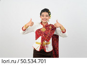 Portrait Young beautiful woman dress up in Thai northeastern region, standing with smile and thumb up, copy space for insert advertise product on white background. Стоковое фото, агентство Ingram Publishing / Фотобанк Лори