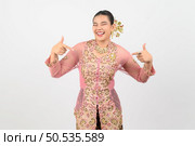 Portrait Young beautiful woman dress up in local culture in southern region with charming gesture smile and point finger two hands on white background, copy space. Стоковое фото, агентство Ingram Publishing / Фотобанк Лори