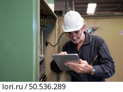 Senior engineer inspects the electrical system and repairs the mechanical system in the machine control cabinet. in order for the machine to return to normal operation. Стоковое фото, агентство Ingram Publishing / Фотобанк Лори