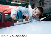 Auto mechanic use an electric polisher to polish the dried car paint. After passing the paint from the car painting room. Стоковое фото, агентство Ingram Publishing / Фотобанк Лори