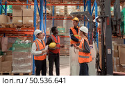 Managers, foremen and warehouse workers Consult together about getting the goods out of the warehouse to finish sending the small merchants tonight. Стоковое фото, агентство Ingram Publishing / Фотобанк Лори