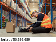 A warehouse employee was injured in an accident. because the product package fell from the shelves and crushed the employee’s leg severely. Стоковое фото, агентство Ingram Publishing / Фотобанк Лори