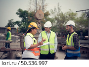 Group of architects, construction foremen, and construction engineers review the work and talk about how the project, in the construction site. Стоковое фото, агентство Ingram Publishing / Фотобанк Лори