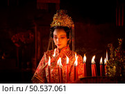 Chinese woman make wishes, pray, and light candles. On the occasion of the annual Chinese New Year festival, in a revered shrine or temple, And in Chinese where candles mean good luck and happiness. Стоковое фото, агентство Ingram Publishing / Фотобанк Лори