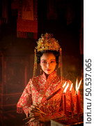 Chinese woman make wishes, pray, and light candles. On the occasion of the annual Chinese New Year festival, in a revered shrine or temple, And in Chinese where candles mean good luck and happiness. Стоковое фото, агентство Ingram Publishing / Фотобанк Лори