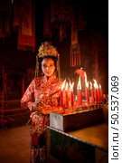 Chinese woman make wishes, pray, and light candles. On the occasion of the annual Chinese New Year festival, in a revered shrine or temple, And in Chinese where candles mean good luck and happiness. Стоковое фото, агентство Ingram Publishing / Фотобанк Лори