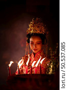 Chinese woman make wishes, pray, and light candles. On the occasion of the annual Chinese New Year festival, in a revered shrine or temple, And in Chinese where candles mean good luck and happiness. Стоковое фото, агентство Ingram Publishing / Фотобанк Лори