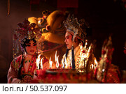 Male and female Chinese opera actors Light a candle to pray homage to the gods to enhance the prosperity for yourself on the occasion of the Chinese New Year festival. Стоковое фото, агентство Ingram Publishing / Фотобанк Лори