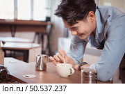 Before competing in the championship level coffee brewing competition, Young baristas practice their coffee latte makeup techniques to become proficient. Стоковое фото, агентство Ingram Publishing / Фотобанк Лори