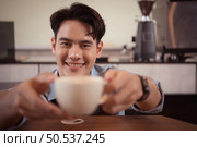 Young barista with the intention of making up a latte coffee to satisfy customers both in appearance and taste, This cup of coffee is ready to be served. Стоковое фото, агентство Ingram Publishing / Фотобанк Лори