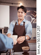 Young barista with the intention of making up a latte coffee to satisfy customers both in appearance and taste, This cup of coffee is ready to be served. Стоковое фото, агентство Ingram Publishing / Фотобанк Лори