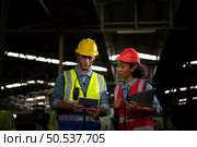 The foreign chief engineer came to inspect the old mechanical factory. There is an African female mechanic explaining details and progress reports on old machines being repaired to restore normal operation. Стоковое фото, агентство Ingram Publishing / Фотобанк Лори