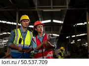 The foreign chief engineer came to inspect the old mechanical factory. There is an African female mechanic explaining details and progress reports on old machines being repaired to restore normal operation. Стоковое фото, агентство Ingram Publishing / Фотобанк Лори