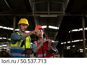 The foreign chief engineer came to inspect the old mechanical factory. There is an African female mechanic explaining details and progress reports on old machines being repaired to restore normal operation. Стоковое фото, агентство Ingram Publishing / Фотобанк Лори