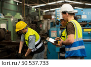 The foreign chief engineer came to inspect the old mechanical factory. There is an African female mechanic explaining details and progress reports on old machines being repaired to restore normal operation. Стоковое фото, агентство Ingram Publishing / Фотобанк Лори