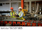 Two young engineers Testing and verifying the operation of the machines forming metal sheet tiles in the factory. Стоковое фото, агентство Ingram Publishing / Фотобанк Лори