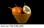 Passion fruit maracuja granadilla on ceramic yellow bowl, black background. Стоковое фото, агентство Ingram Publishing / Фотобанк Лори