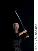 Senior Japanese samurai with katana sword on black background, studio shot. Стоковое фото, агентство Ingram Publishing / Фотобанк Лори
