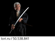 Senior Japanese samurai with katana sword on black background, studio shot. Стоковое фото, агентство Ingram Publishing / Фотобанк Лори