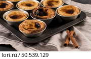 Rows of freshly cooked egg tarts, traditional portuguese dessert, pastel de nata, custard tarts on metal tray. Стоковое фото, агентство Ingram Publishing / Фотобанк Лори