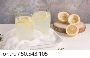 Cold lemonade or alcoholic cocktail with lemon, rosemary and ice in glass glasses on a light background. Стоковое фото, агентство Ingram Publishing / Фотобанк Лори