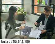 Both of businessperson sitting on stairs in office talk and exchange ideas on using natural energy in buildings before entering the meeting to present and consider. Стоковое фото, агентство Ingram Publishing / Фотобанк Лори