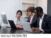 Group of business people wearing headset working actively in office. Call center, telemarketing, customer support agent provide service on telephone video conference call. Стоковое фото, агентство Ingram Publishing / Фотобанк Лори