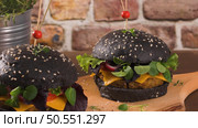 Tasty grilled veggie burger with lentils, dry tomato and thyme with black bread on wooden countertop. Стоковое фото, агентство Ingram Publishing / Фотобанк Лори
