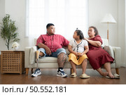 A plus size family with a father wearing a prosthetic leg, Resting and talking with daughter on the weekly holiday, in the living room of the house. Стоковое фото, агентство Ingram Publishing / Фотобанк Лори