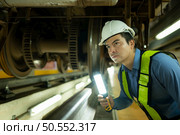 Engineers for electric trains After detecting difficulties with the electric train’s machinery use searchlights to locate and check damaged sections. In the electric train repair shop. Стоковое фото, агентство Ingram Publishing / Фотобанк Лори