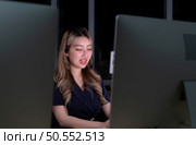 Young Asian woman broker international stock traders wearing headset working actively at night in office, Concept of customer support agent provide service on telephone. Стоковое фото, агентство Ingram Publishing / Фотобанк Лори