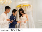 Bridal gown designers and tailors measure the size of the gown against the bride’s figure when she comes to try on the gown in order to make it perfect and ready to wear on the wedding day. Стоковое фото, агентство Ingram Publishing / Фотобанк Лори