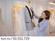 Asian fashion designers make sure the groom’s outfit is absolutely accurate and ready for the bride and groom to try on. Стоковое фото, агентство Ingram Publishing / Фотобанк Лори