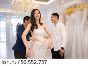 Bridal gown designers and tailors measure the size of the gown against the bride’s figure when she comes to try on the gown in order to make it perfect and ready to wear on the wedding day. Стоковое фото, агентство Ingram Publishing / Фотобанк Лори