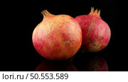 Ripe pomegranate fruit with leaves on black background. Стоковое фото, агентство Ingram Publishing / Фотобанк Лори